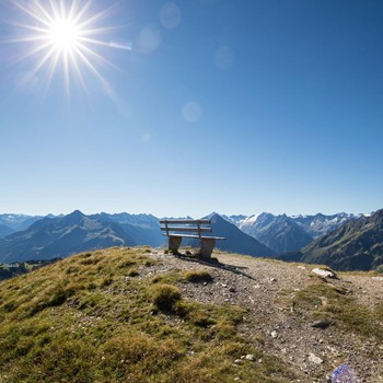 Sunny viewpoint with bench and panoramic view of the Zillertal Alps.