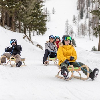 Familie rodelt fröhlich durch die verschneite Winterlandschaft in Finkenberg.